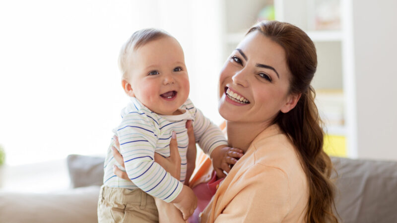 family, child and motherhood concept - happy smiling young mother with little baby at home