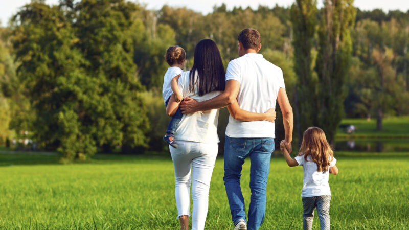 Rear view. Happy family with children walking in the park. Mother, father and children in nature.